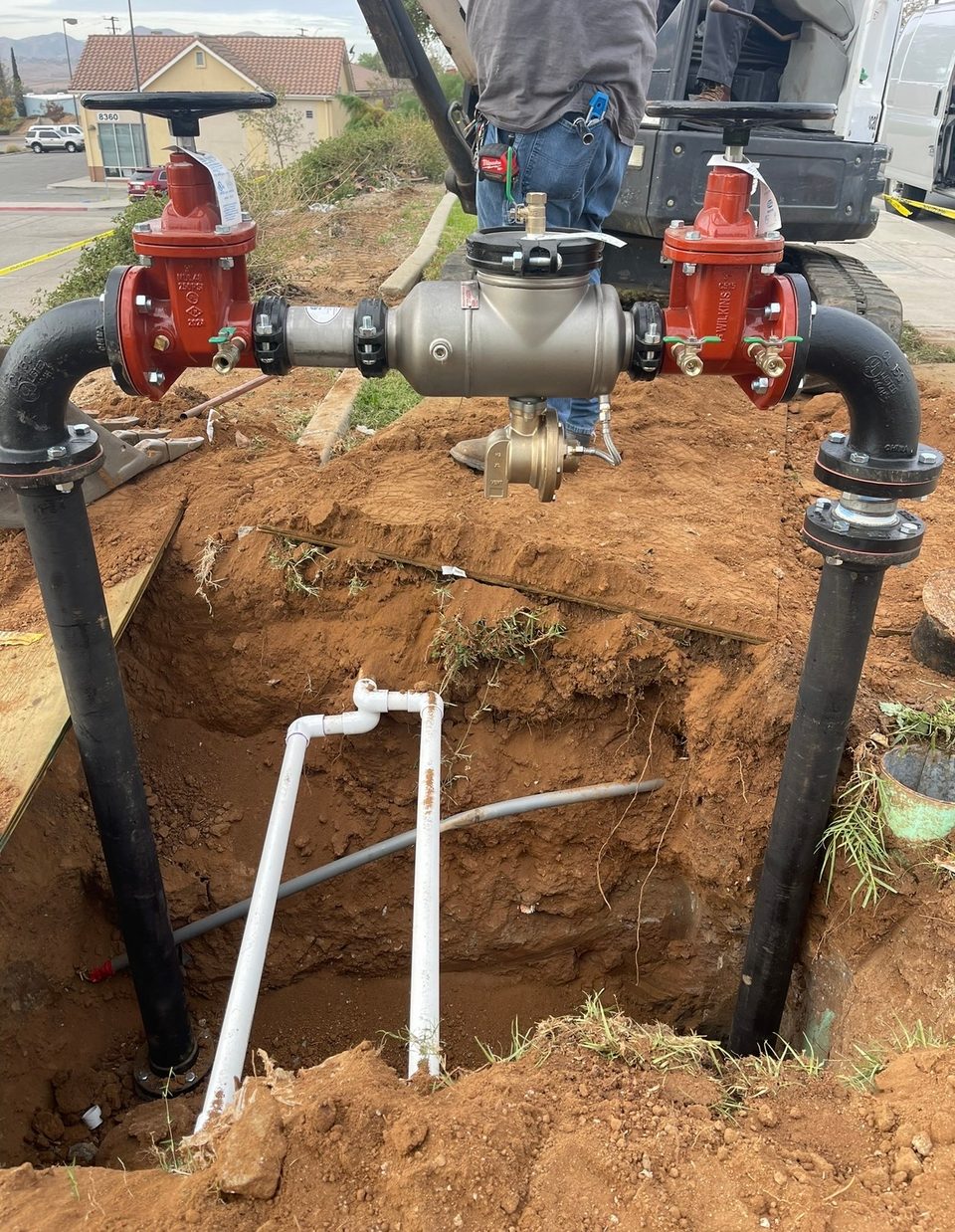 Large commercial backflow prevention assembly with red gate valves being set on a new water service line