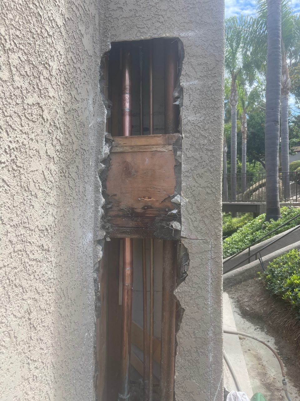 New copper water line running inside an opened stucco exterior wall during a repipe
