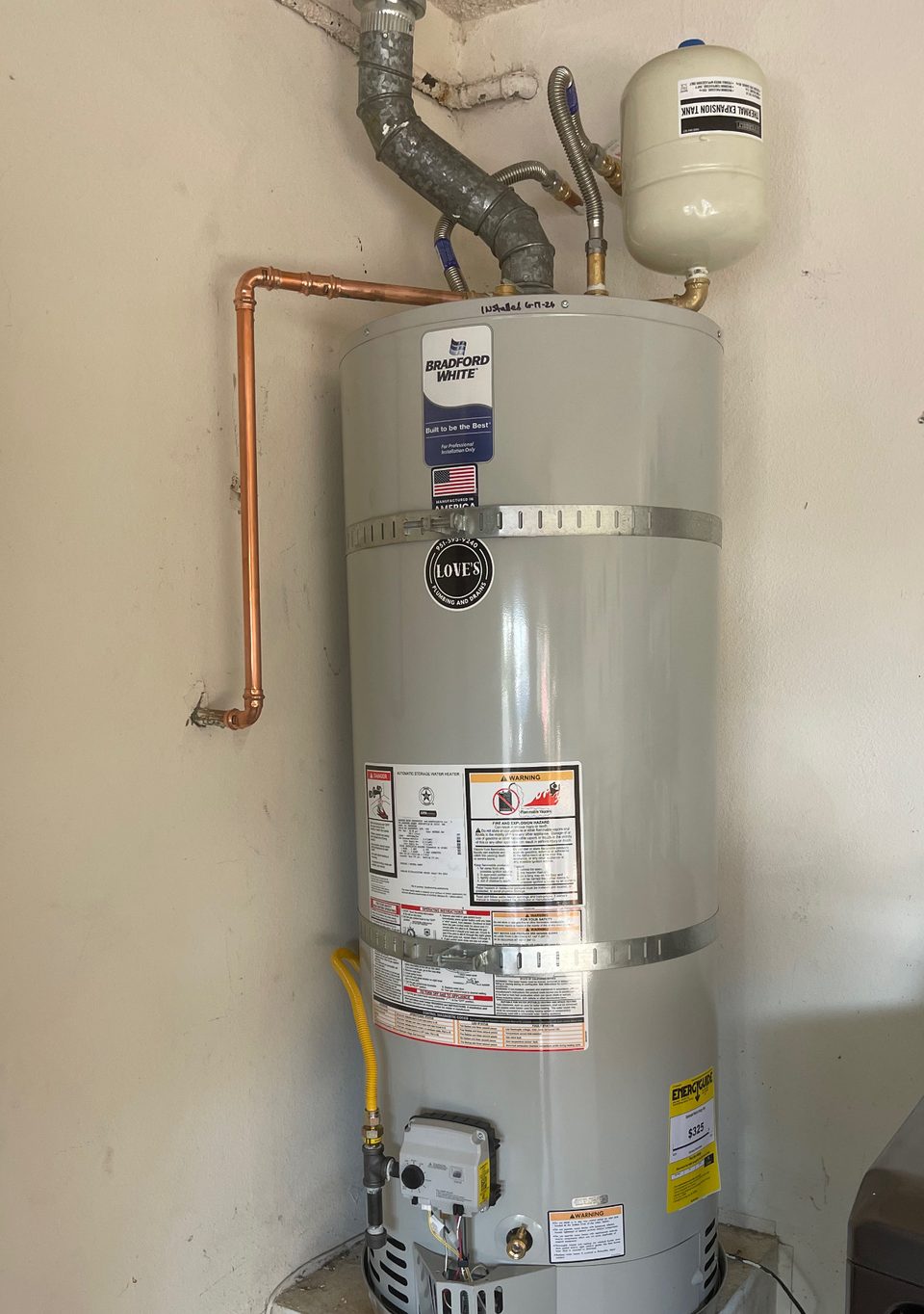Newly installed residential tank water heater with expansion tank, copper connections and a gas shutoff valve